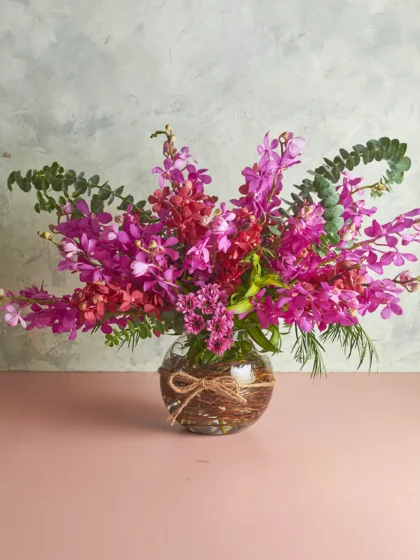 Bountiful in-vase arrangement with pink and red mokara orchids and eucalyptus in a round glass vase - Mahua Mumbai
